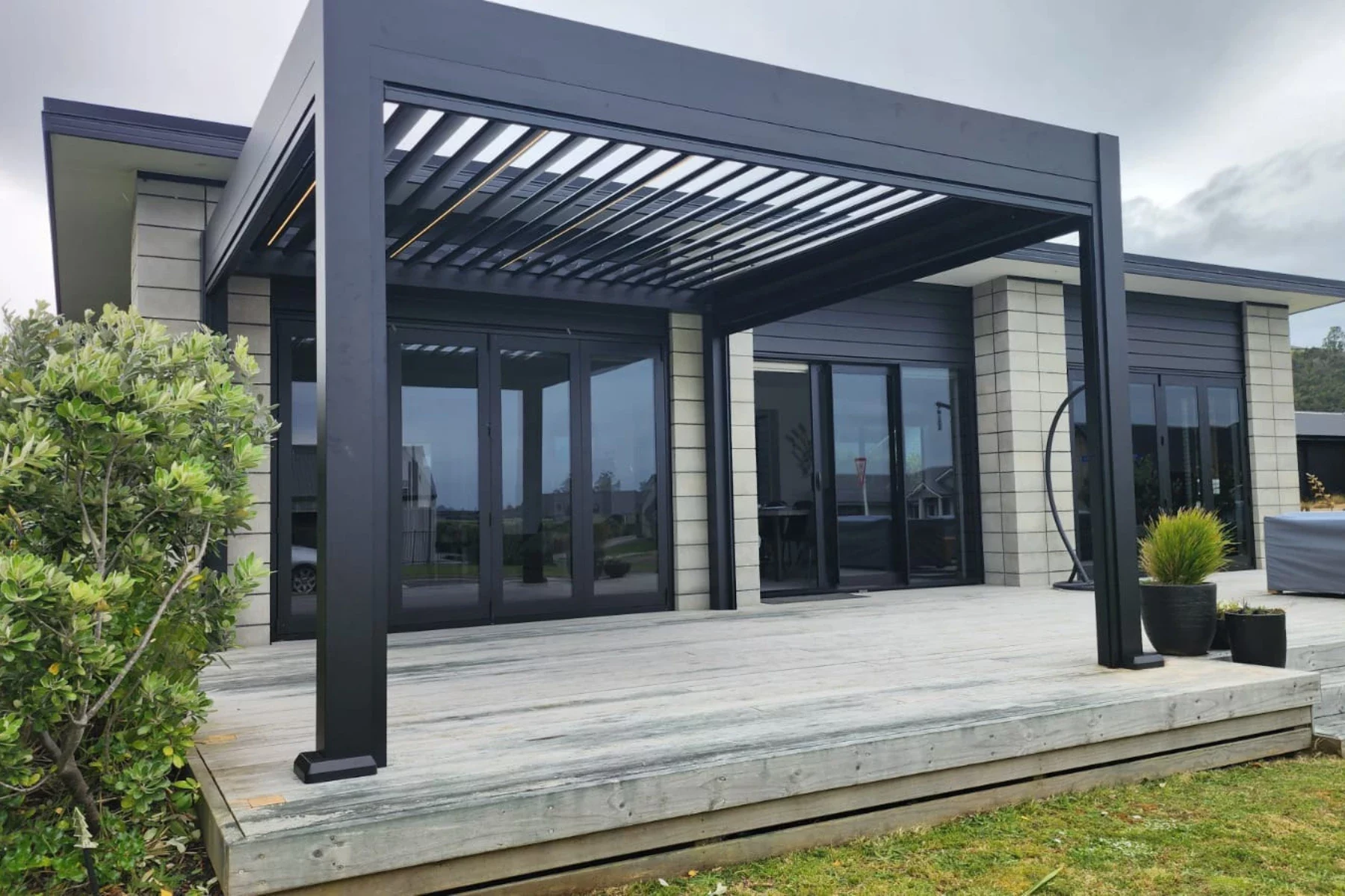 Pergola mit offenem Lamellendach und Glasfront